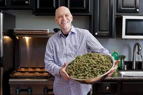 אדם מחזיק קערה ענקית מלאה בפרחי קנאביס