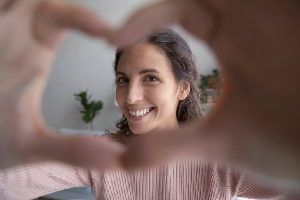 אשה נחמדה עושה צורת לב עם הידיים