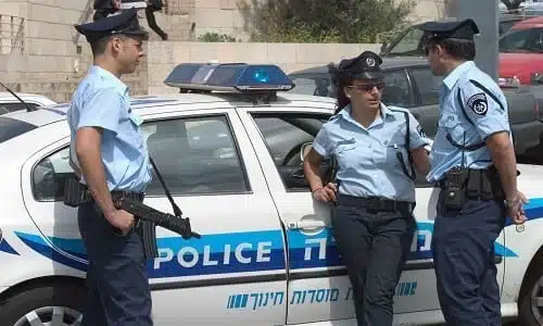 שלושה שוטרים בישראל נשענים על ניידת