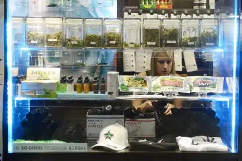 אישה בוחרת קנאביס לרכישה מתוך חלון תצוגה בחנות קנאביס בקולורדו