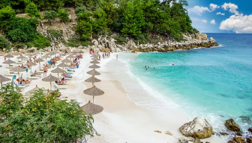 חוף שיש (חוף סאליארה), איי תאסוס, יוון. החוף הלבן הכי יפה ביוון. תיירים נהנים מיום נחמד על החוף. שמשיות קש (שמשיית קש) ומיטות שיזוף על החוף.